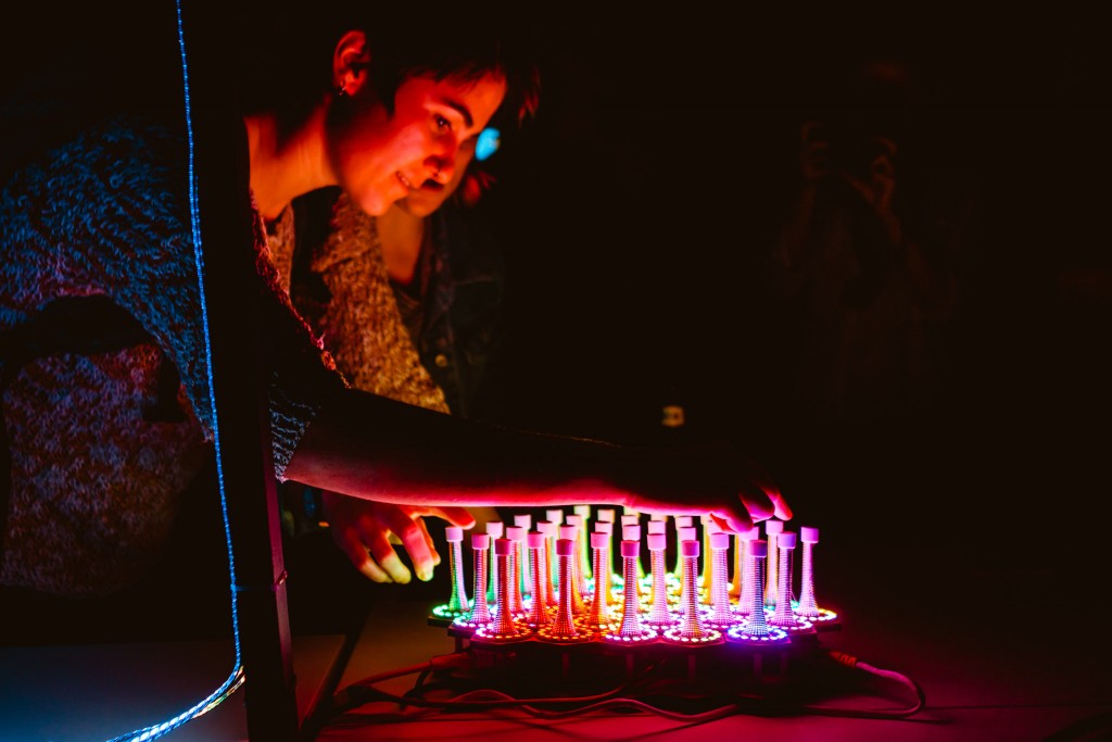 Two people playing a brightly lit collection of LED lit springs. 